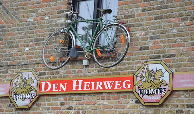 Hangende fiets boven uithangbord Den Heireweg